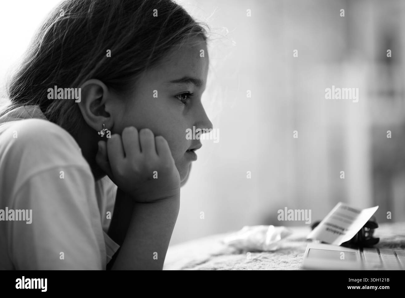 Thoughtful child watching educational content on digital device at home Stock Photo