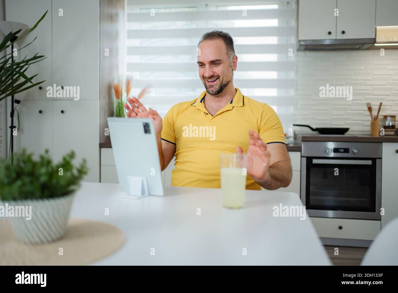 Man having video call on tablet in home kitchen Stock Photo