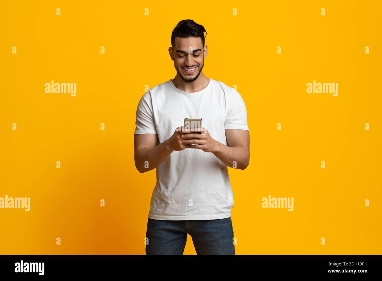 Happy middle eastern man using smartphone and smiling Stock Photo