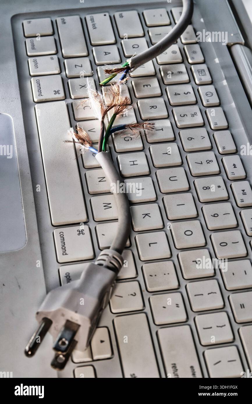 Still life of a frayed computer power cord on a laptop keyboard, 2026, United States Stock Photo