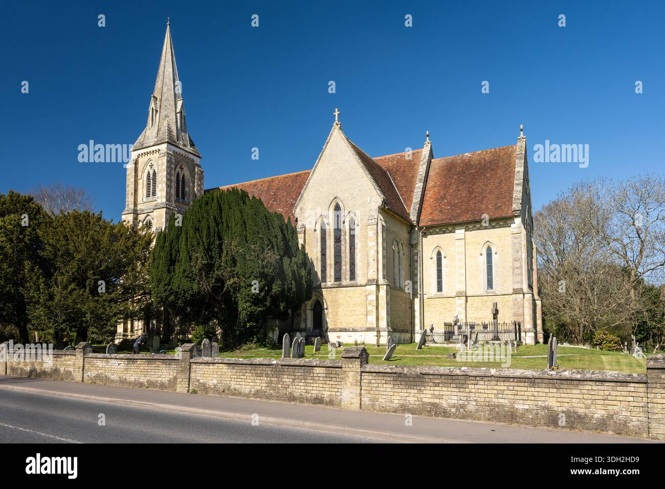 Sun shines on the traditional gothic parish church of St John the Apostle in Marchwood, Hampshire. Stock Photo