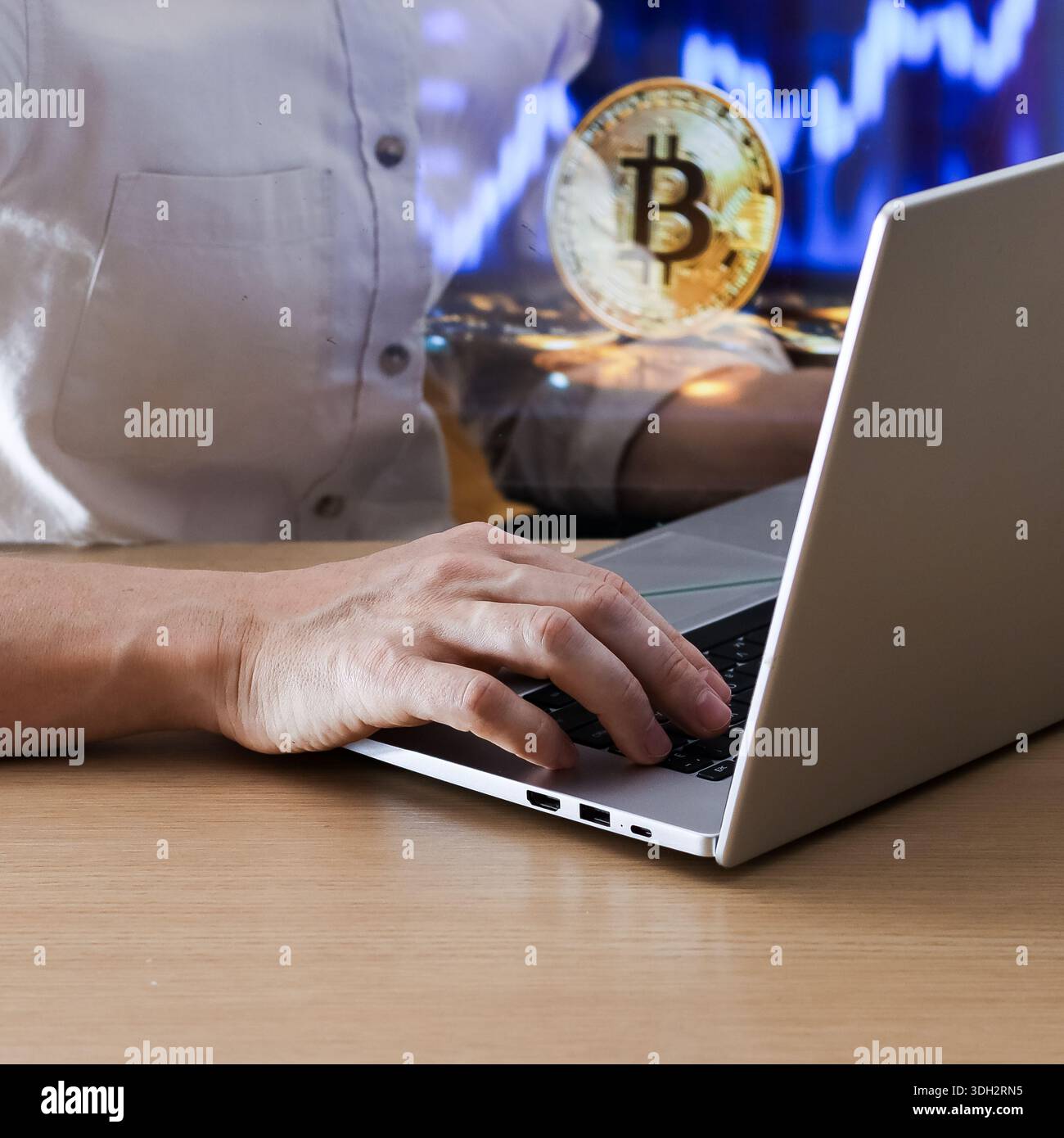 Focused shot of typing on notebook computer with glowing coin and market data overlay. Stock Photo