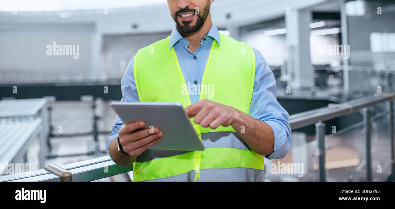 Construction Worker Using Tablet at Building Site During Work Hours for Project Management Stock Photo
