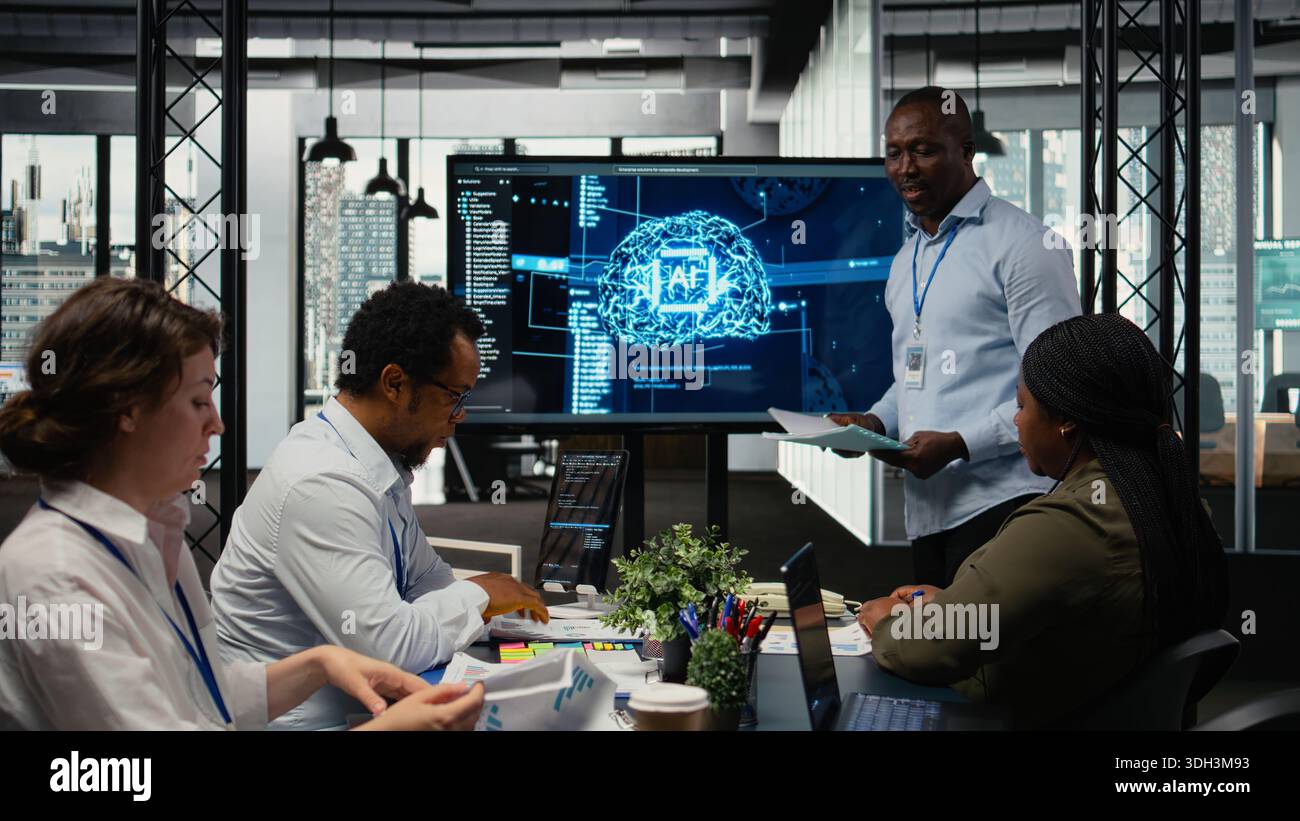 Programmer gives presentation to executives, implementing AI chatbot reducing work volume. Startup office IT expert analyzing business insights for management using artificial intelligence, camera A Stock Photo
