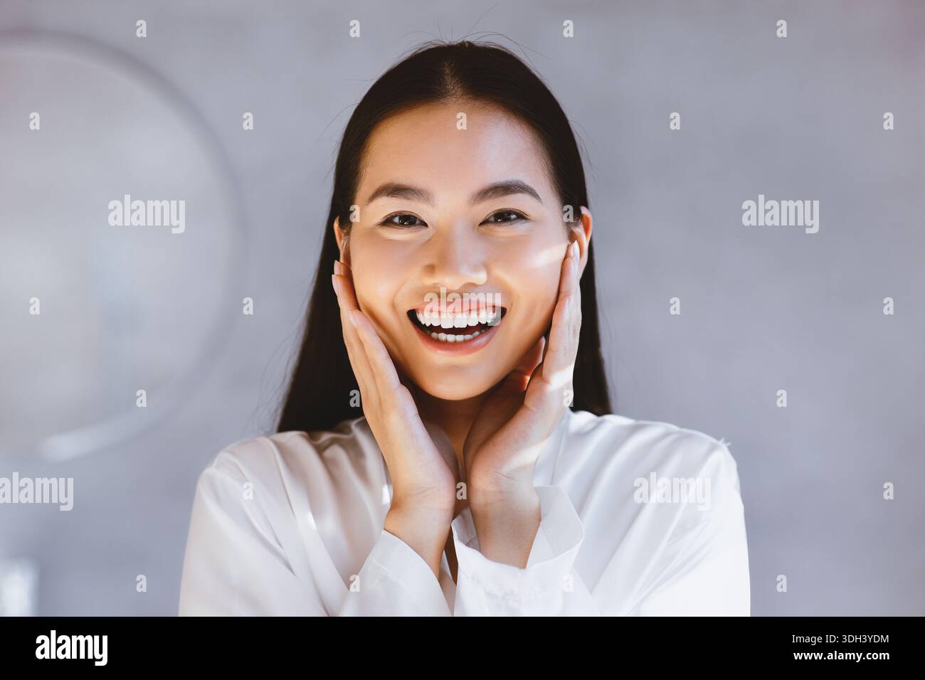 Woman Smiles Broadly While Holding Her Face With Both Hands in a Bright ...