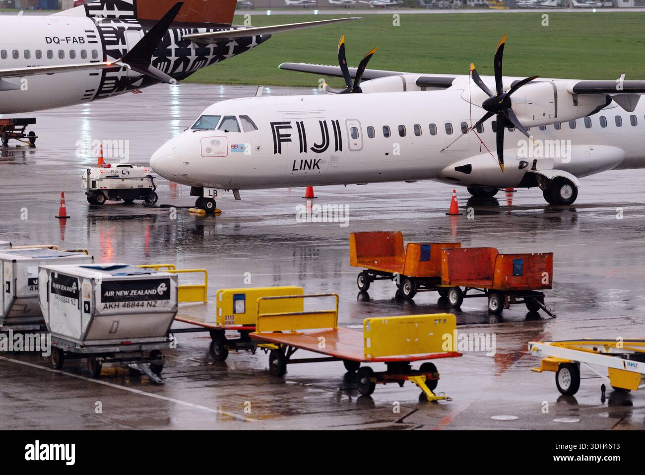 A Fiji Link turboprop aircraft sits on a rain-soaked apron at Nadi ...