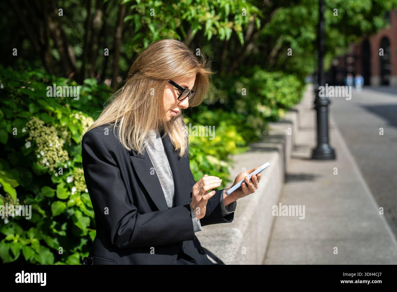 Smiling woman checking messages outside hi-res stock photography and ...