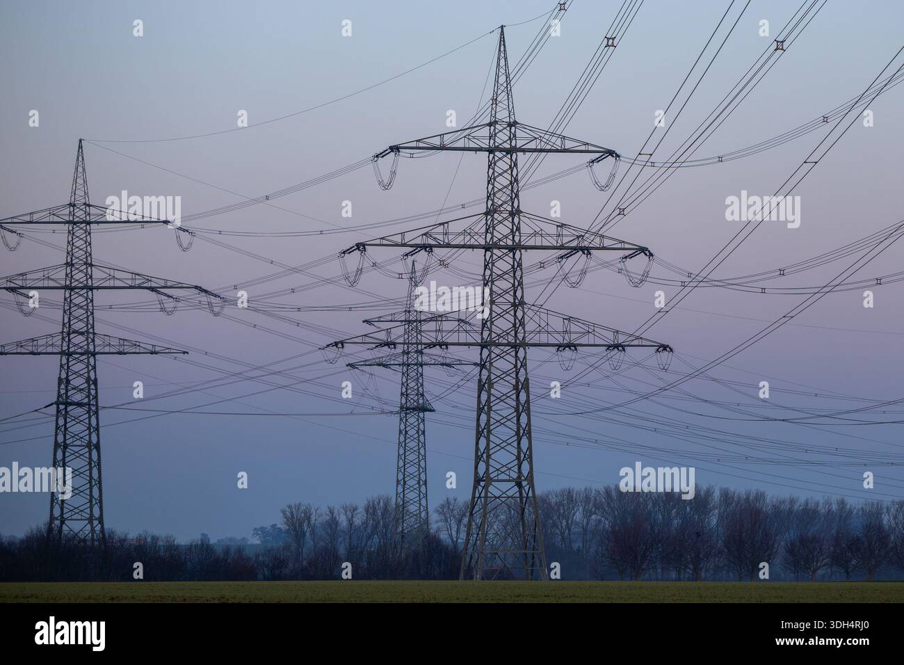 High-voltage transmission towers and power lines silhouetted against a ...