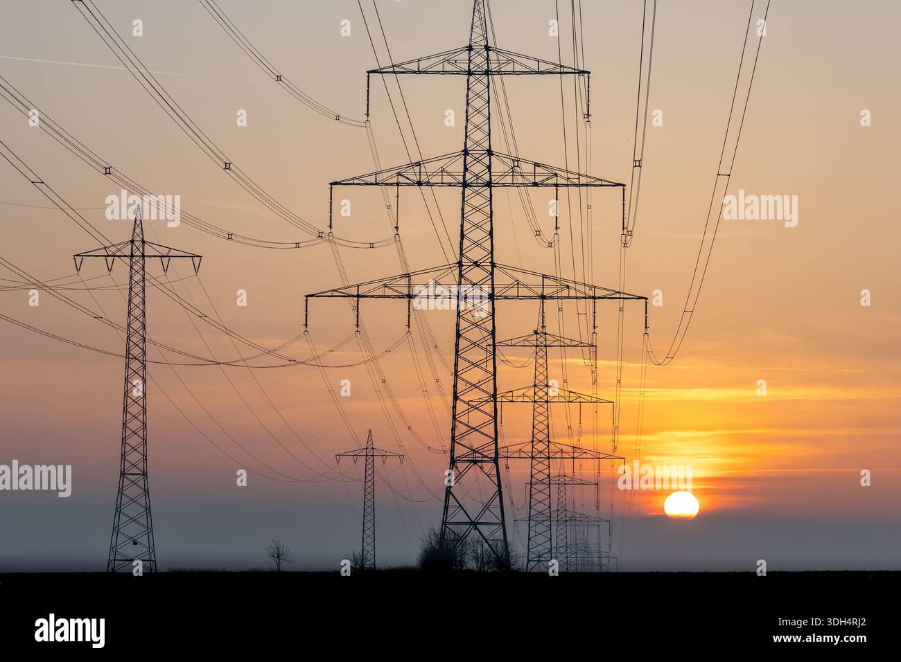 High-voltage transmission towers and power lines silhouetted against a ...