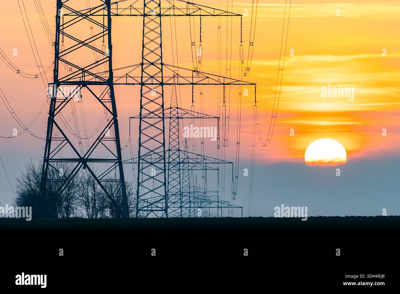 High-voltage transmission towers and power lines silhouetted against a ...