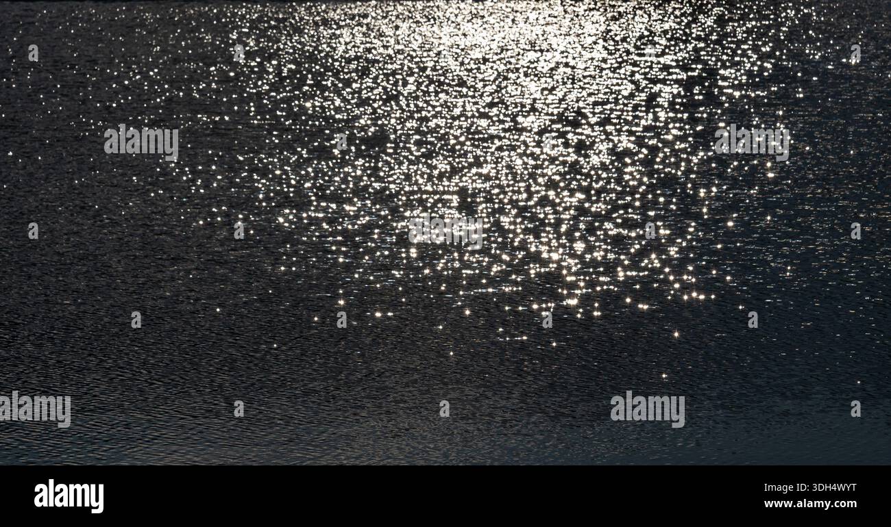 Sunlight sparkling across a rippled lake surface Stock Photo