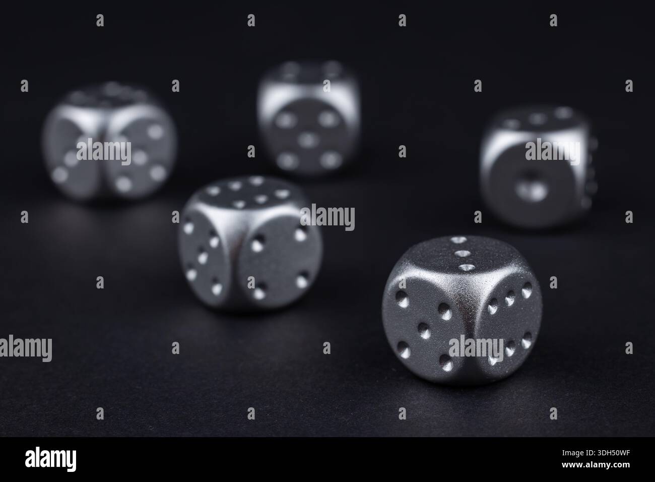 five silver dice view from above on black background. Stock Photo