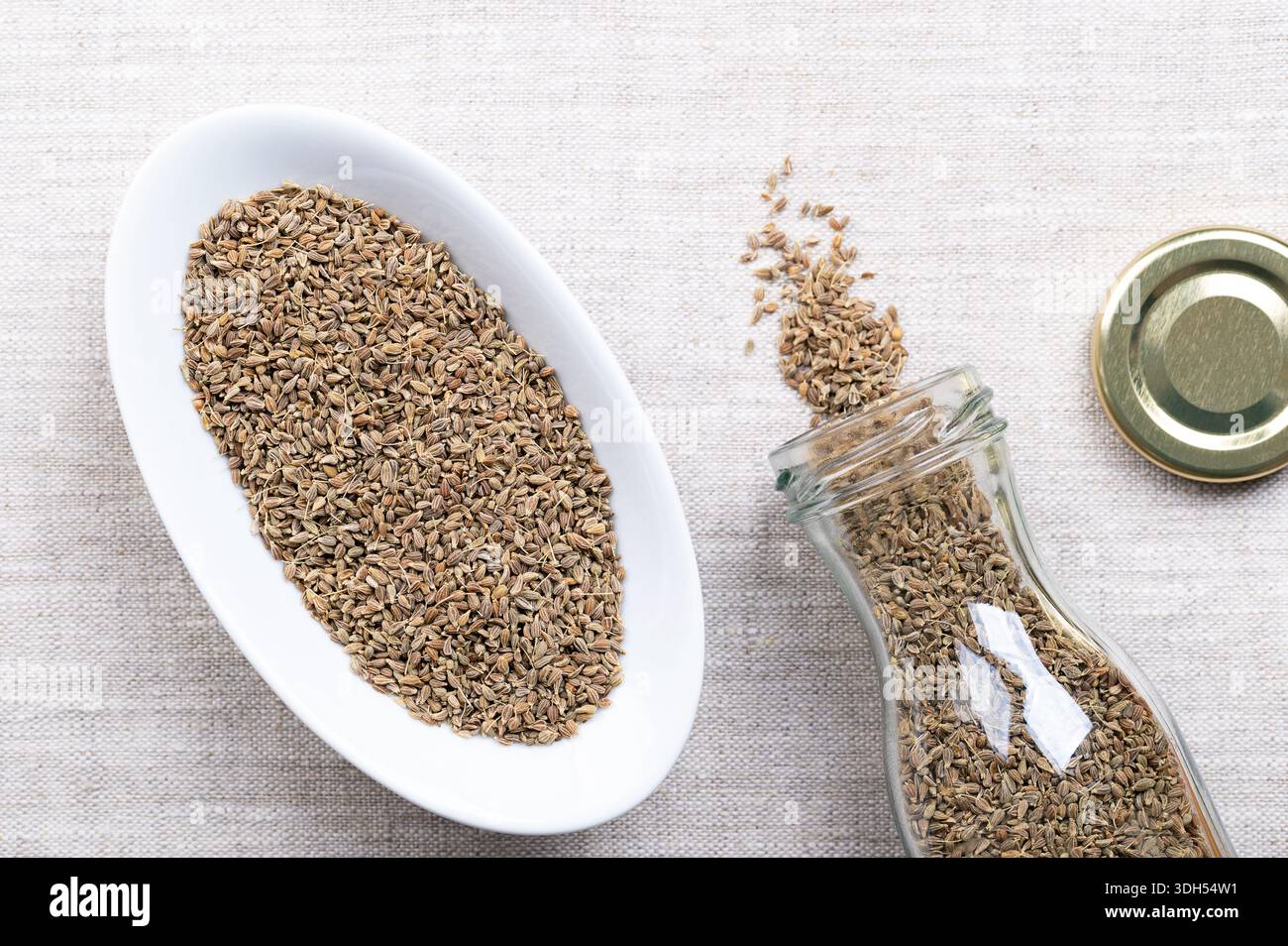 Aniseed, anise seeds in white bowl on linen. Anise fruits, mistakenly called seeds, from the plant Pimpinella anisum, used to flavor food, candy, etc. Stock Photo