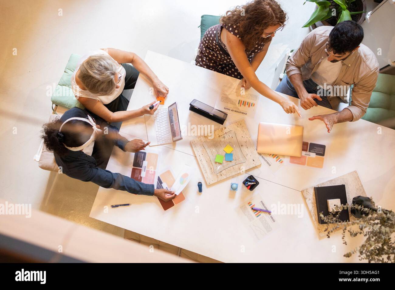 A diverse group of coworkers collaborating around a modern office table, sharing creative ideas and discussing project plans, highlighting teamwork an Stock Photo