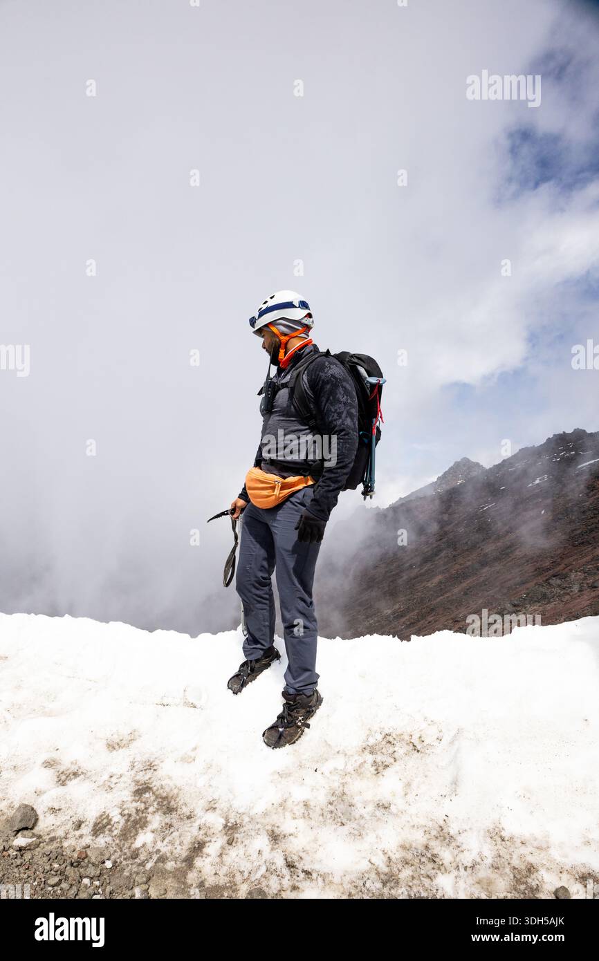 A mountaineer stands on a snowy peak, equipped with essential gear and ...