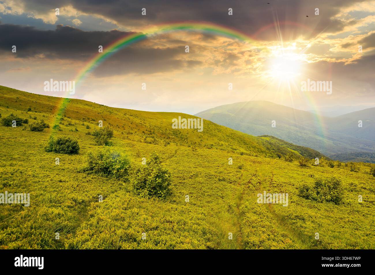 wonderful summer landscape of mountains in at sunset. scenic alpine view of rolling hills and green meadow in evening light. cloudy sky. storytelling Stock Photo