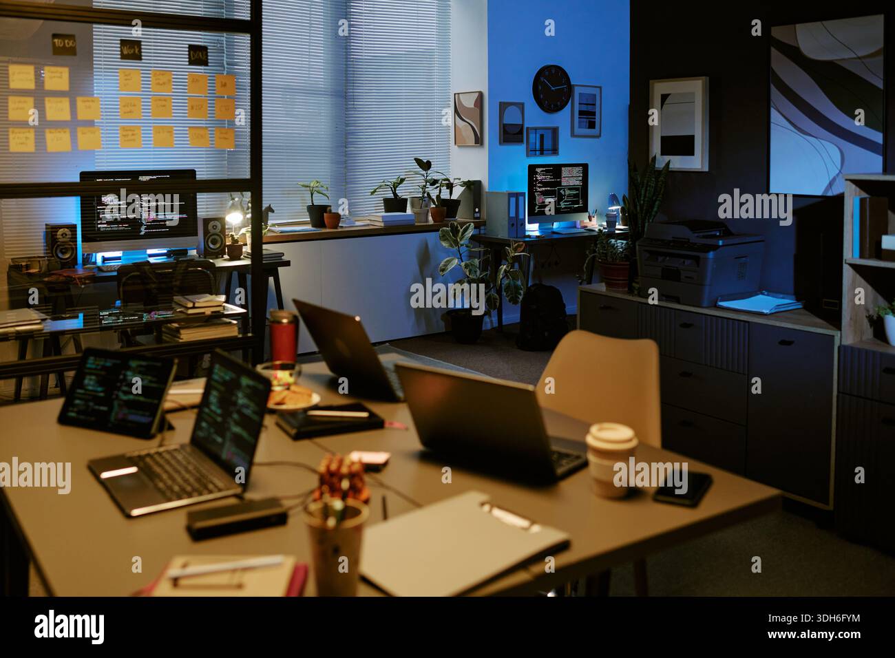 Empty Modern Office Showing Multiple Laptops and Monitors Displaying Code Stock Photo