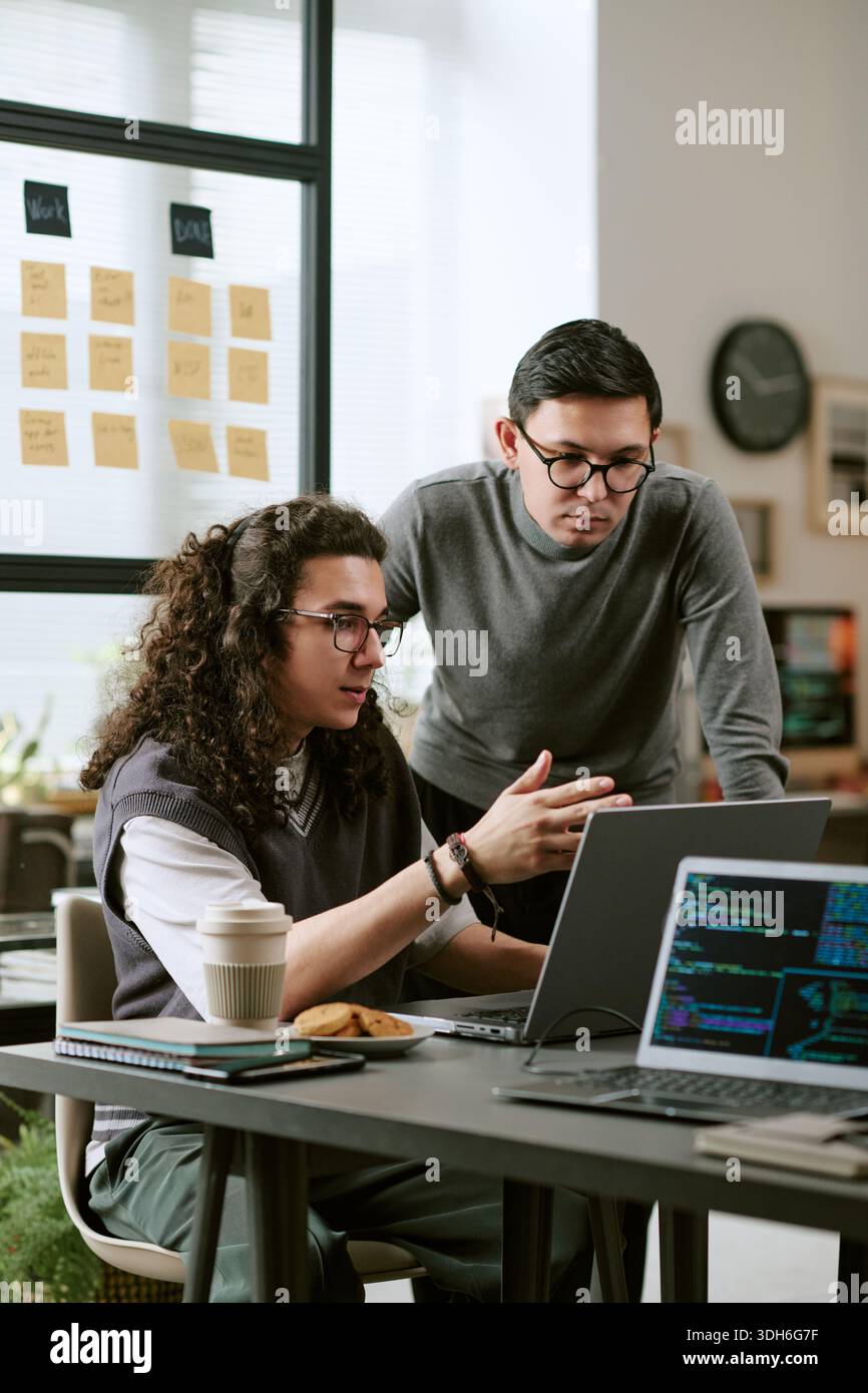 Young Caucasian Colleagues Collaborating on Software Development Project Stock Photo