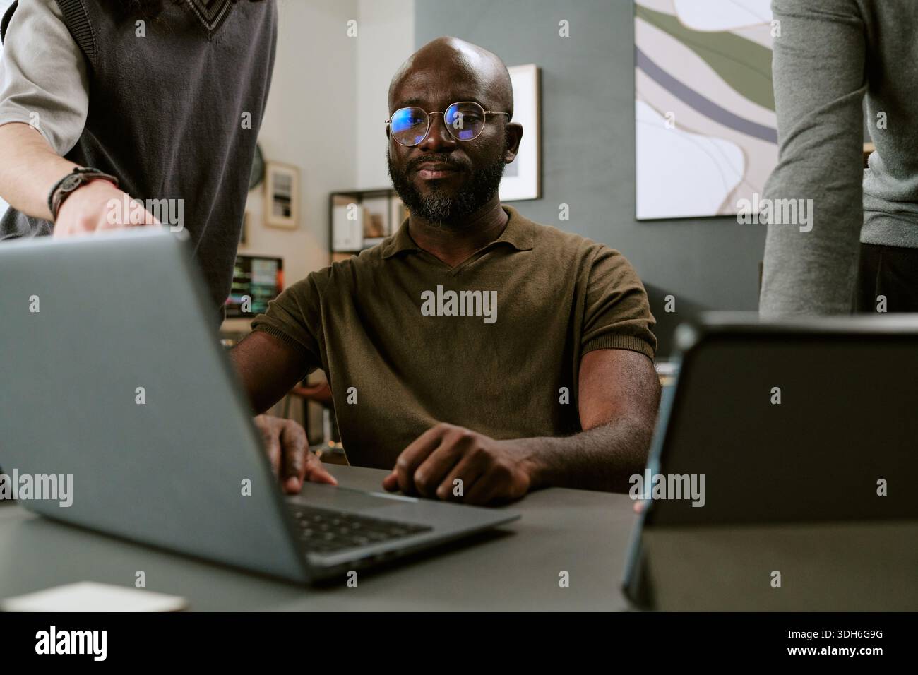 Young Black Man Collaborating with Colleagues in Modern Office Stock Photo