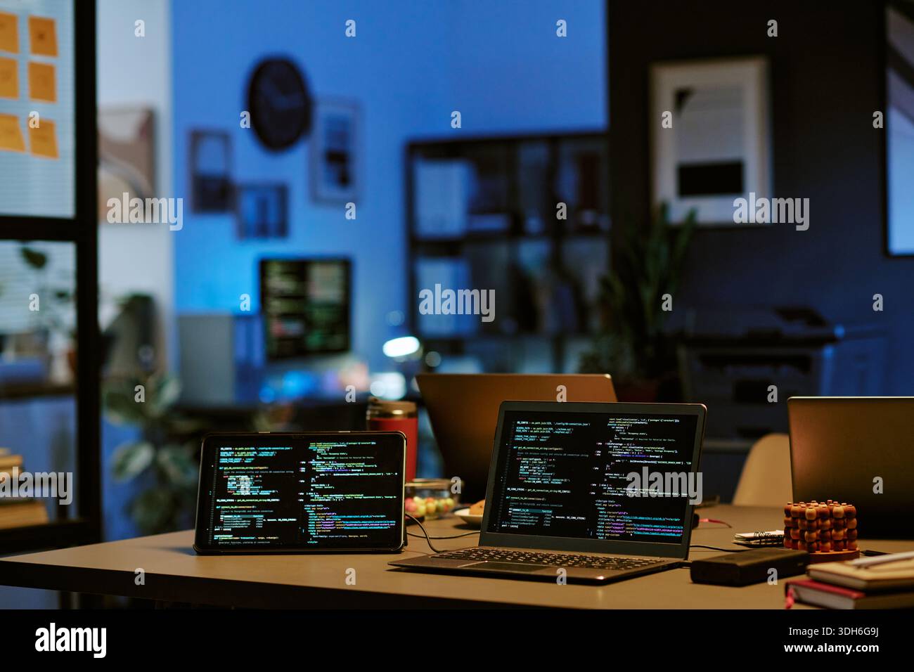 Laptop Computers Displaying Programming Code in Modern Office at Night Stock Photo