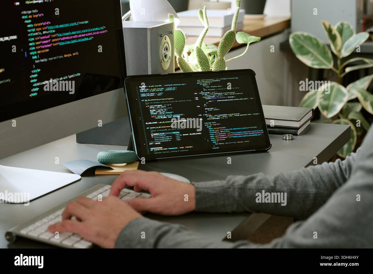 Unrecognizable Man Coding Software on Computer and Tablet in Office Stock Photo
