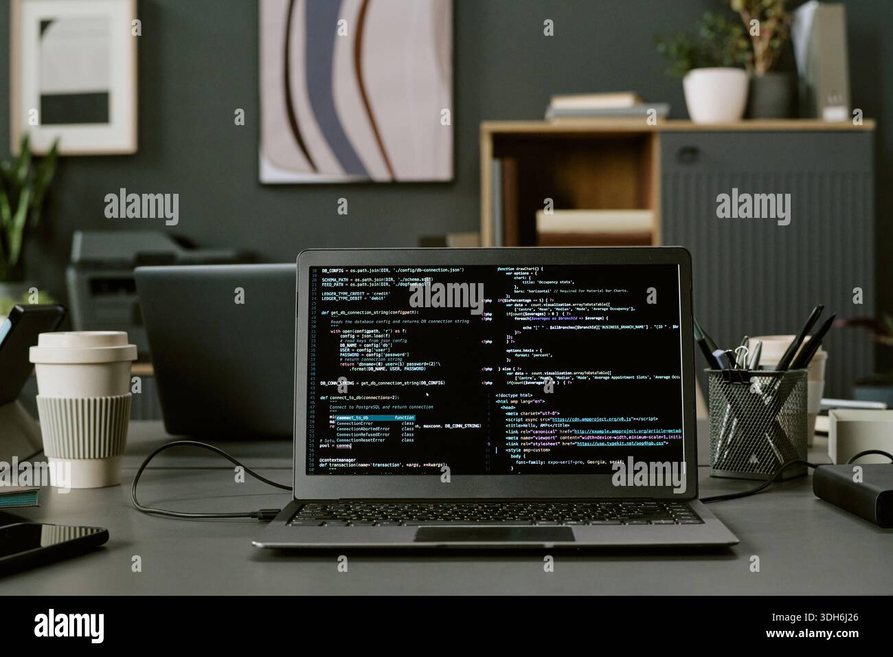 Laptop Displaying Programming Code on Office Desk during Software Development Stock Photo