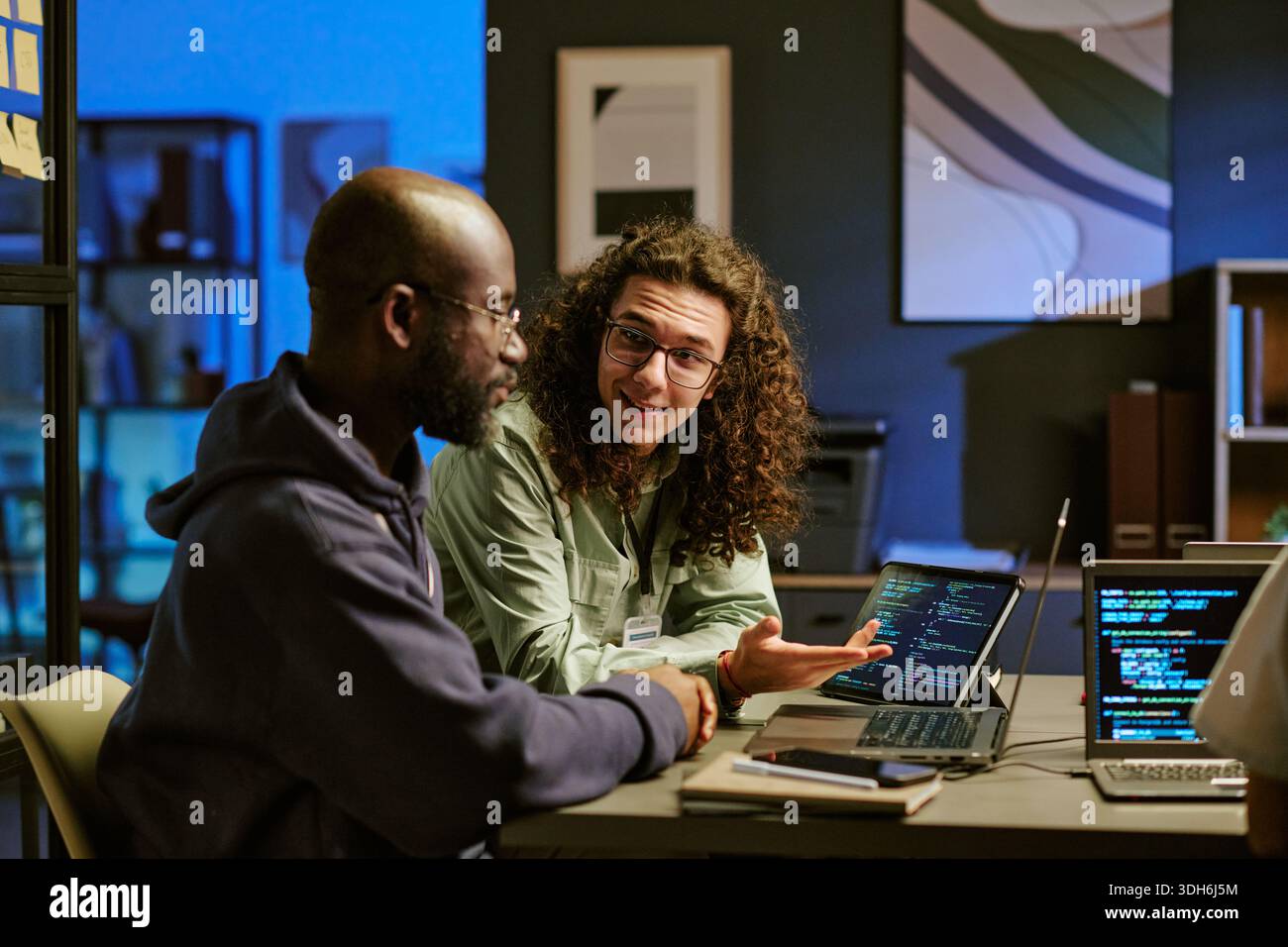 Young Caucasian Man Explaining Programming Code to Black Man in Office Stock Photo