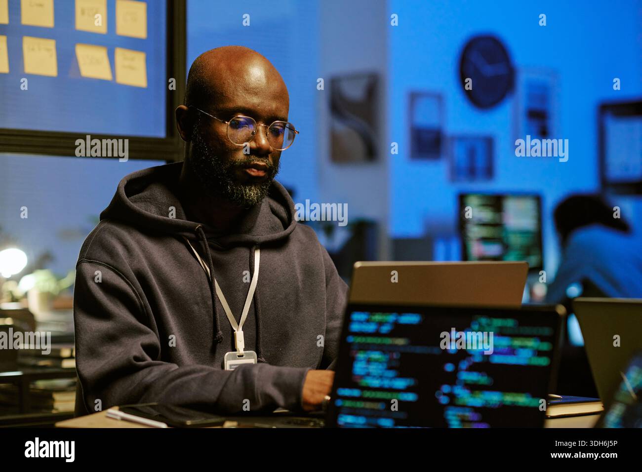 Young Black Man Concentrating on Software Engineering Task at Night Office Stock Photo