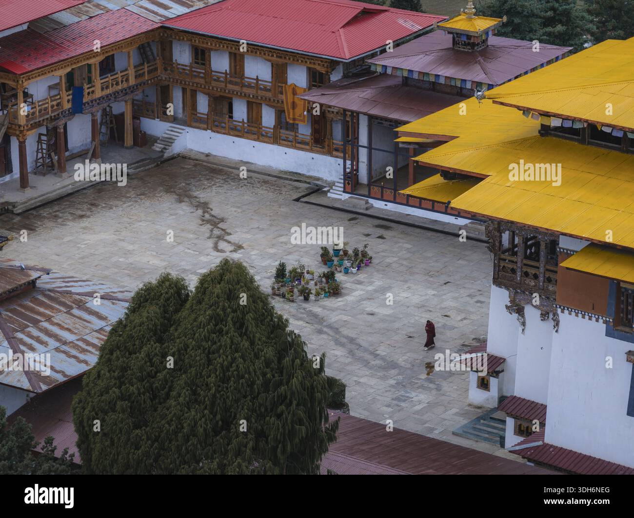 Aerial view of the monastery courtyard with people gathered, framed by vibrant red and yellow roofs, Gangtey Monastery, Nubding, Wangdue Phodrang, Bhu Stock Photo