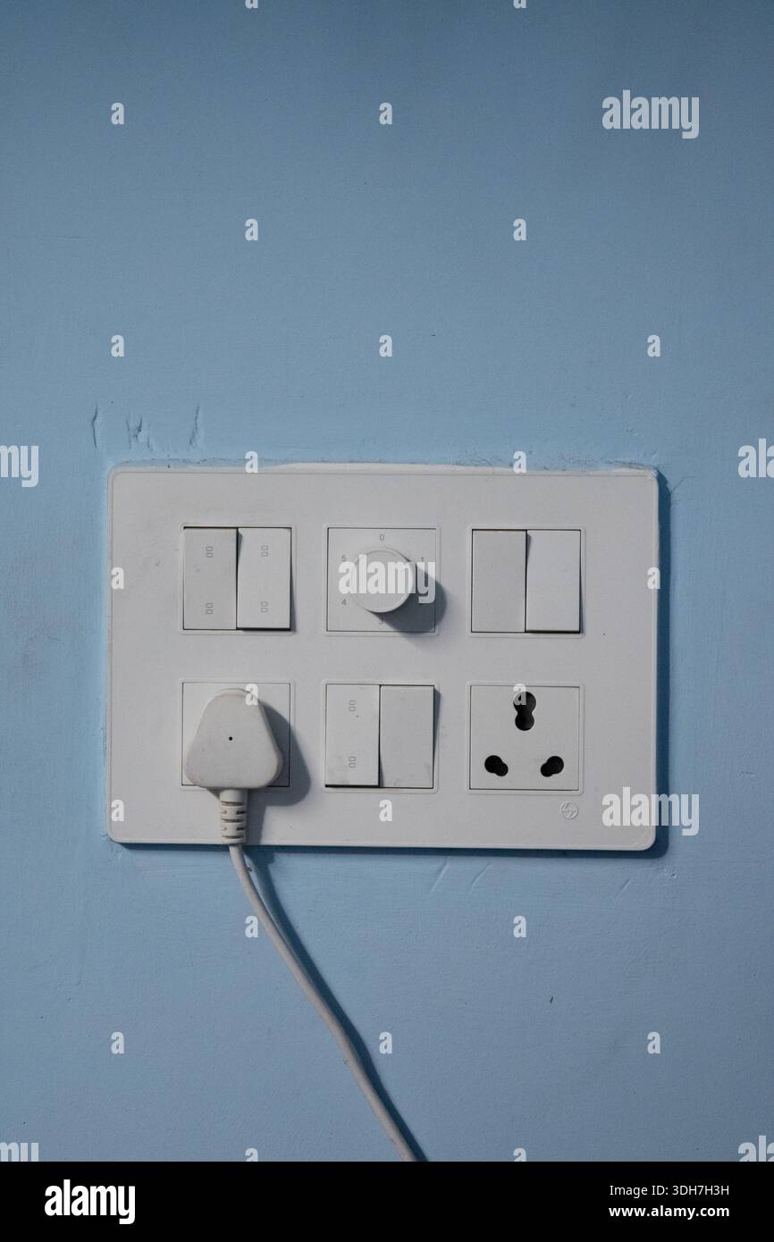 White Electrical Switchboard with Plug on Blue wall Stock Photo