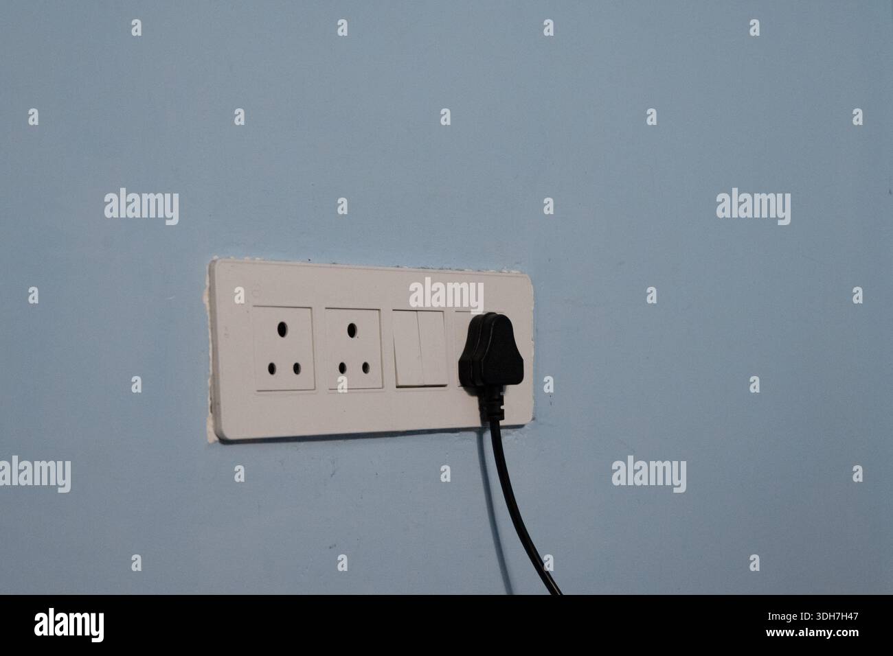White Electrical Switchboard with Plug on Blue wall Stock Photo