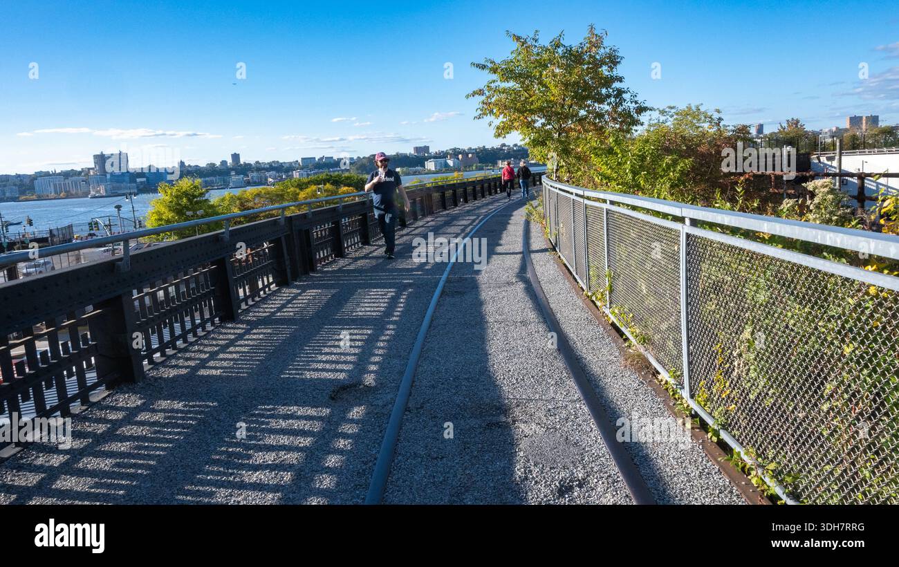 Curved walkway on the High Line with pedestrians and city skyline Stock Photo
