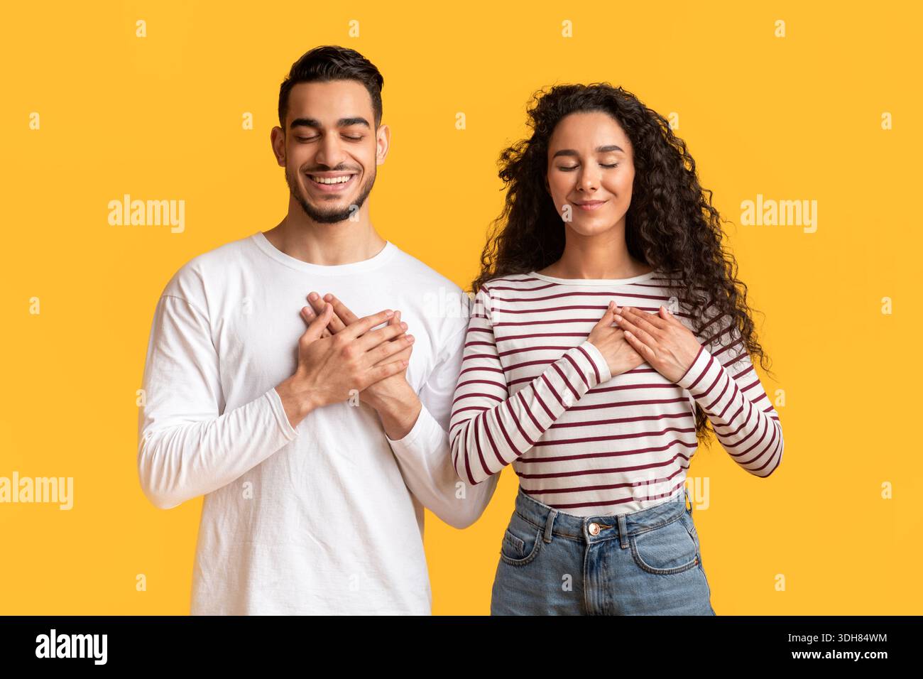 Thank You. Grateful Young Arab Man And Woman Keeping Hands On Chest Stock Photo