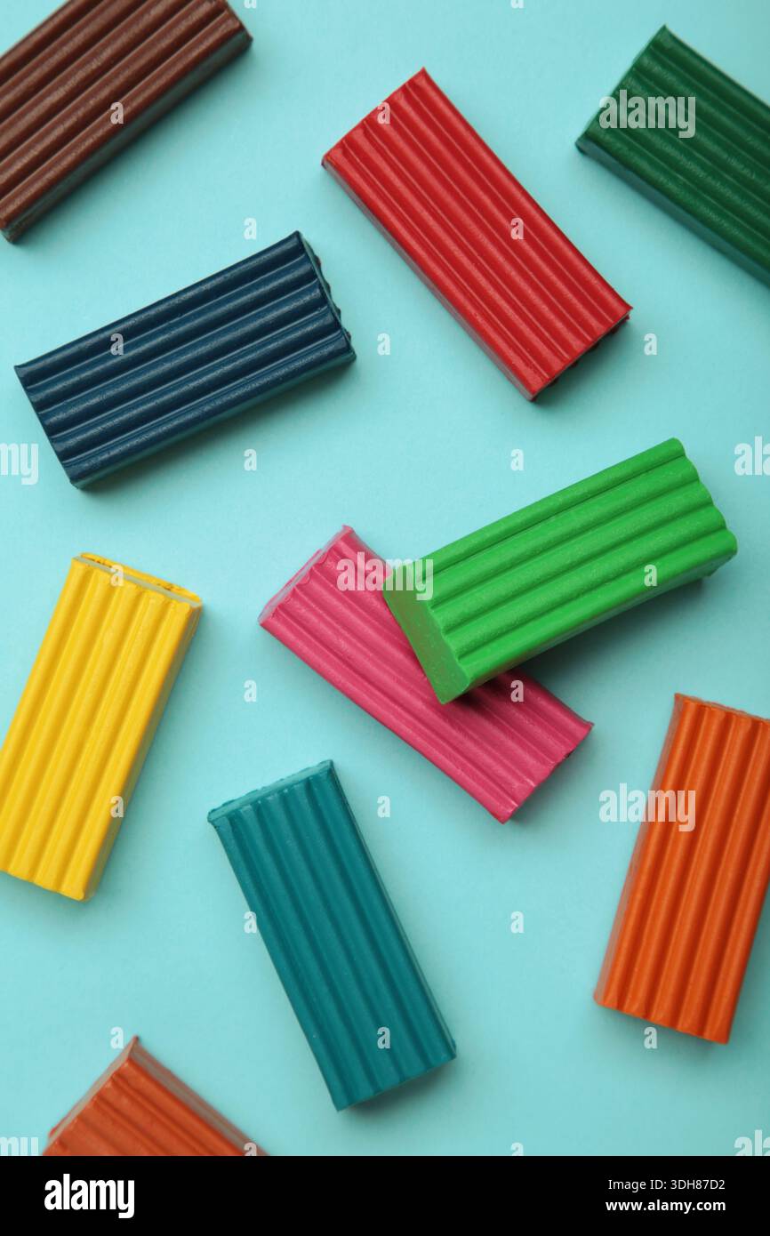 Multi-colored plasticine bricks on blue background. Childrens plasticine close-up. Stock Photo
