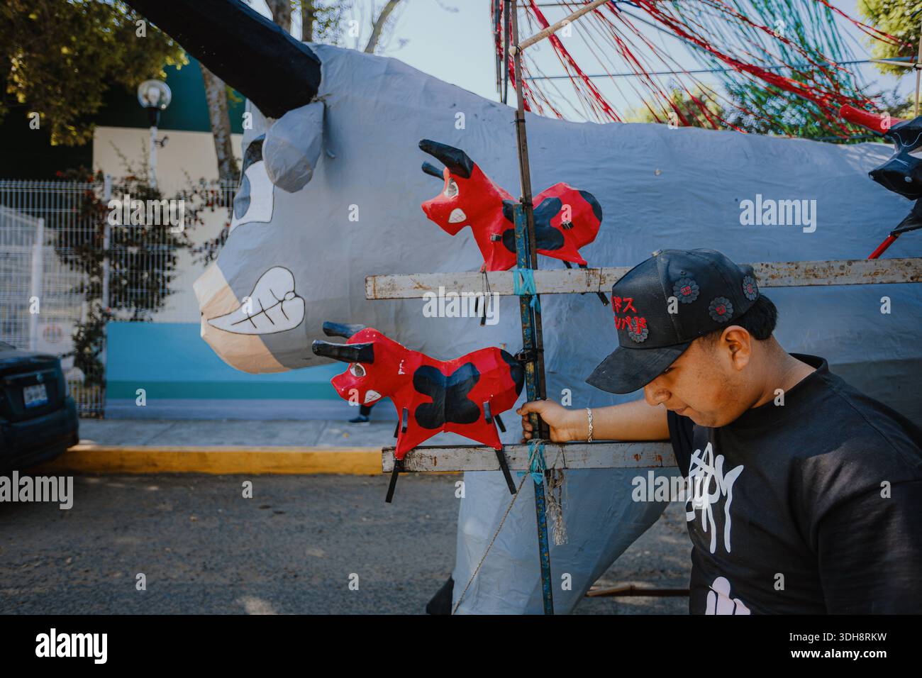 A Mexican artisan next to large cardboard bull structures for folk festivities, showcasing traditional craftsmanship scale and local street culture. Stock Photo