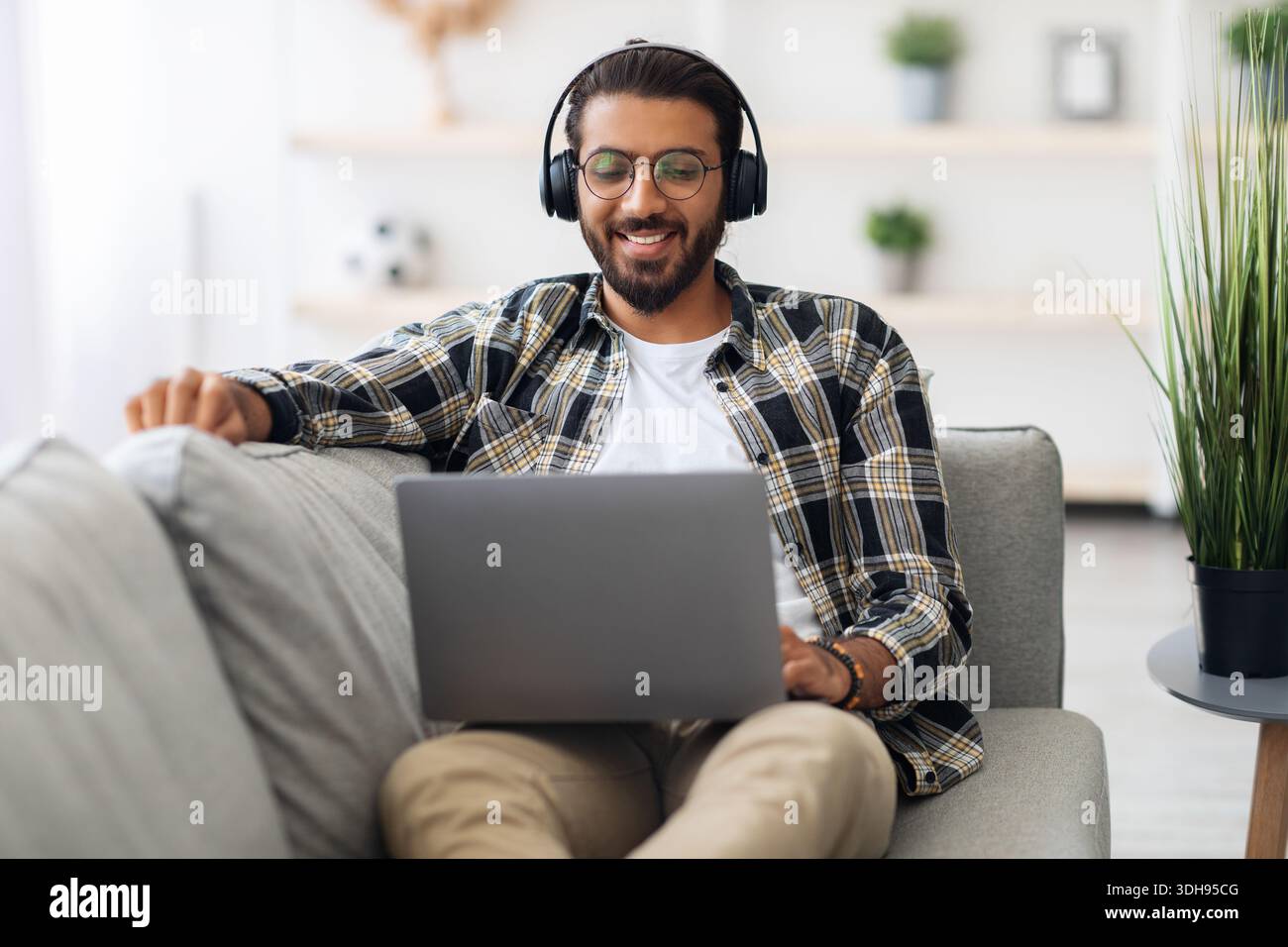 Relaxed middle-eastern guy watching movie online, using laptop Stock Photo