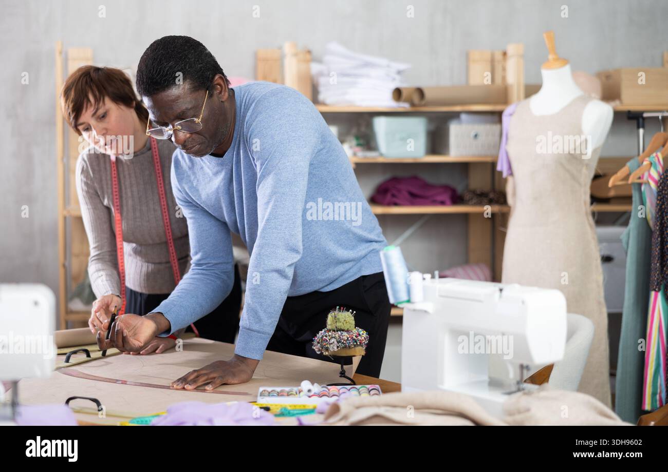 Two sewing workshop workers draw patterns on paper Stock Photo