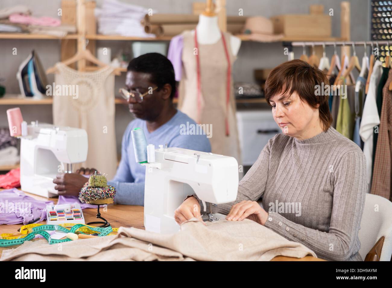 Two tailors working at sewing machines in tailoring studio Stock Photo