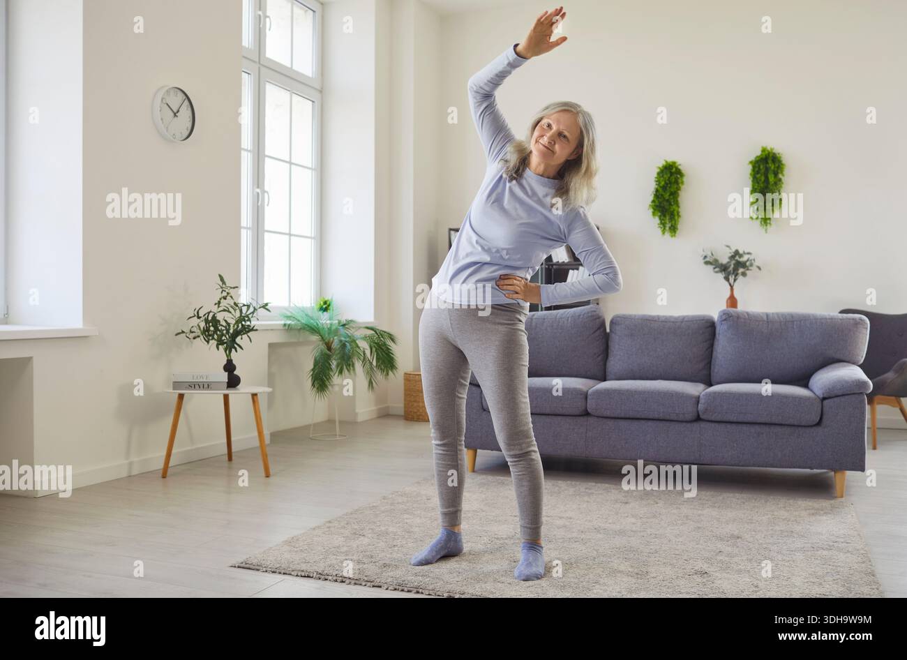 Happy senior woman doing physical exercise, side bends and stretching workout Stock Photo