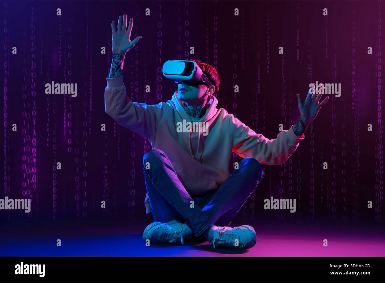Young man using VR glasses on dark background with digital code Stock Photo