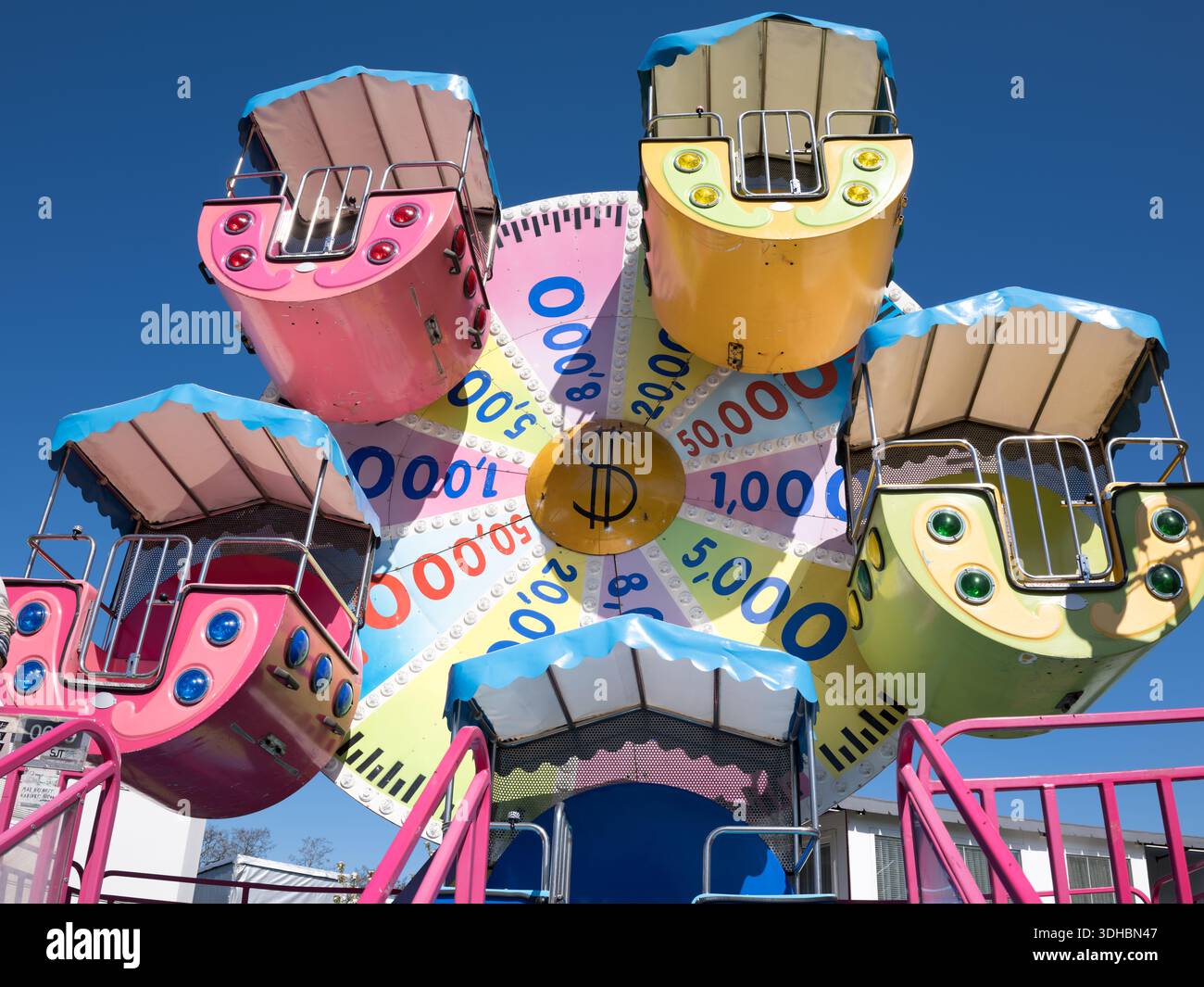 Brightly colored fairground ride cabins and a wheel in an amusement ...