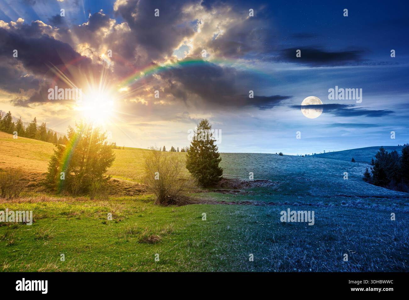 rolling hill with green field under cloudy sky in spring. day and night time change concept. scenic view countryside landscape in mountains with sun a Stock Photo