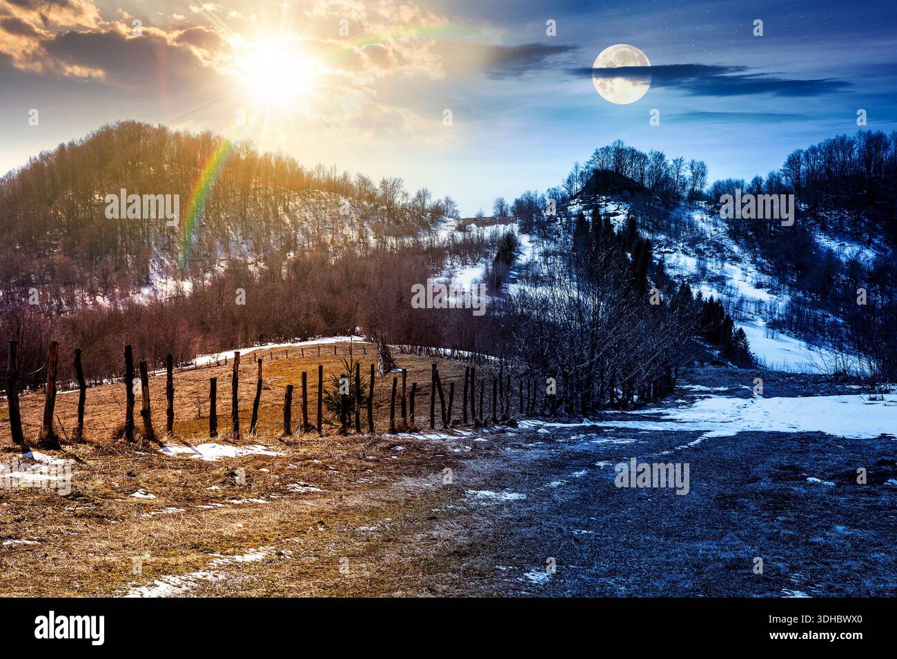 rural landscape in mountains in early spring under blue sky. day and night time change concept. snow covered hill with barbed wire fence with sun and Stock Photo