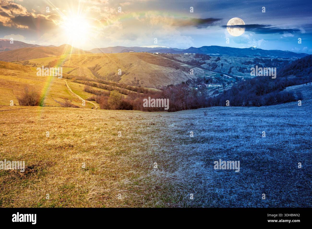 rural landscape with village in valley. day and night time change concept. outdoor adventure in countryside with rolling hill, snowy mountain under su Stock Photo