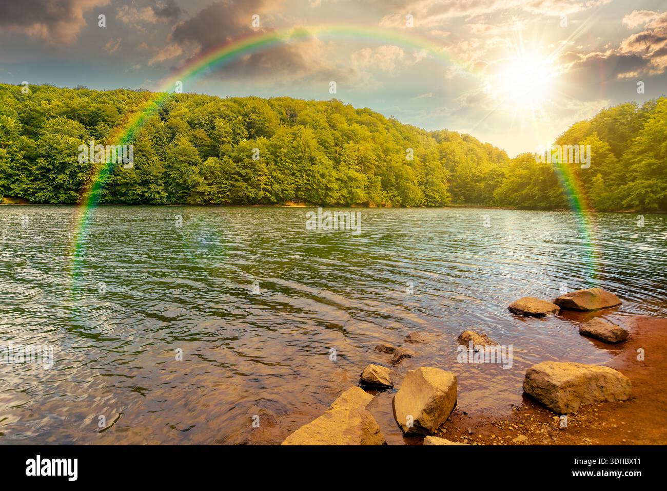 beautiful view of landscape with lake at sunset. body of water among beech forest in mountains in evening light. summer weather with clouds on the sky Stock Photo