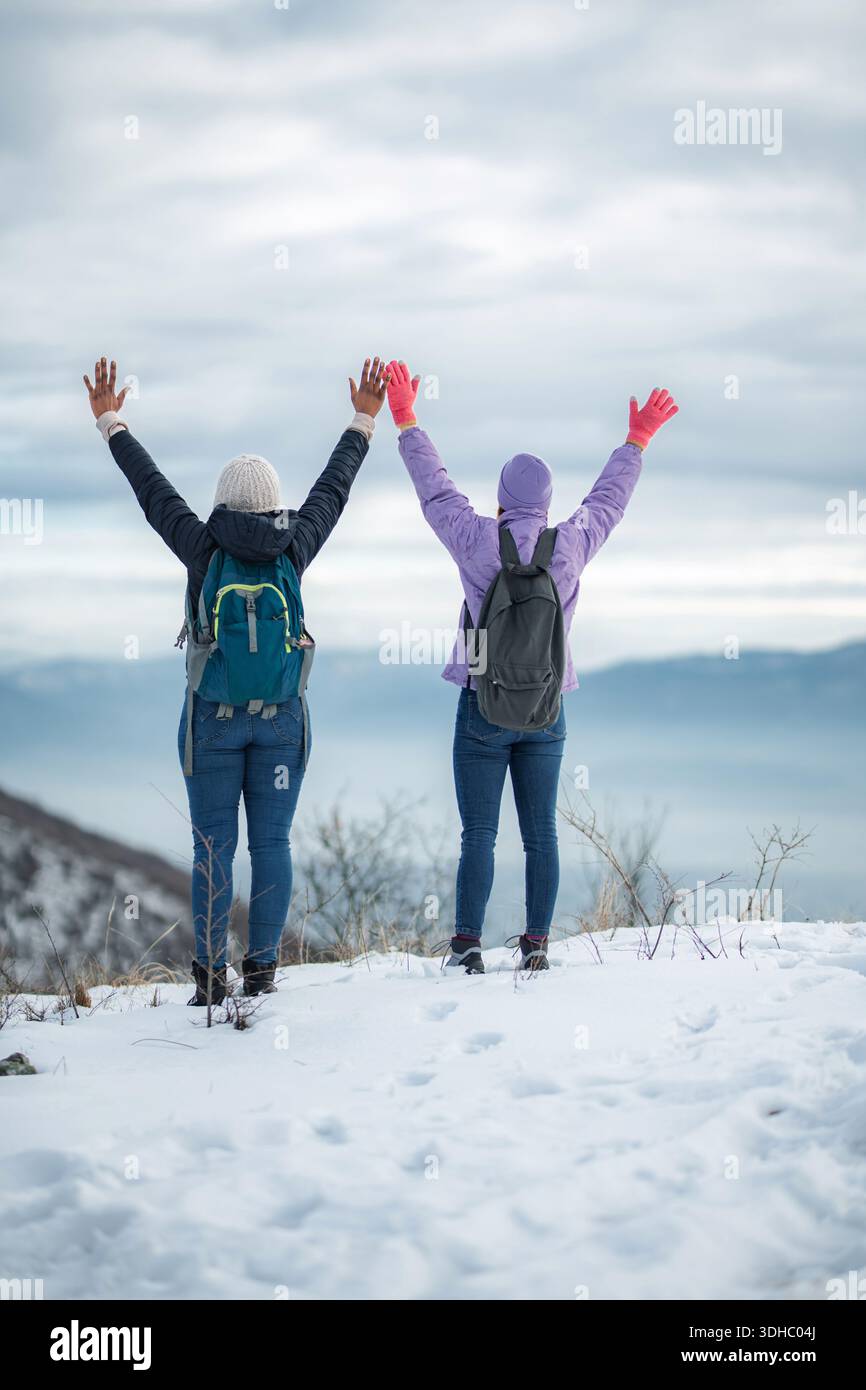 People hiking in snowy mountains celebrating achievement Stock Photo
