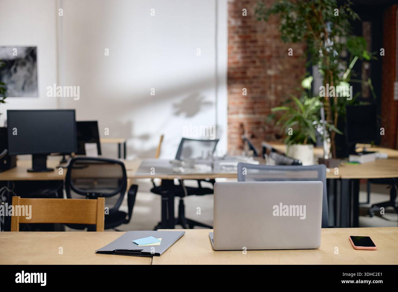 Modern Open Plan Office Workspace Featuring Laptop and Digital Devices Stock Photo