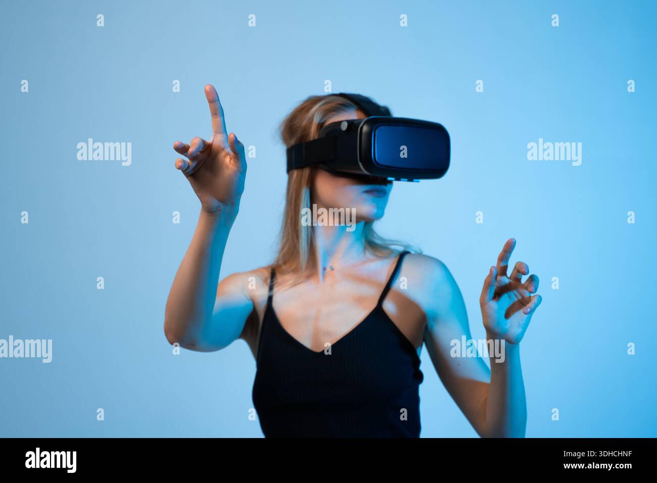 Woman using virtual reality headset and pointing at virtual interface, immersive metaverse experience and future technology Stock Photo