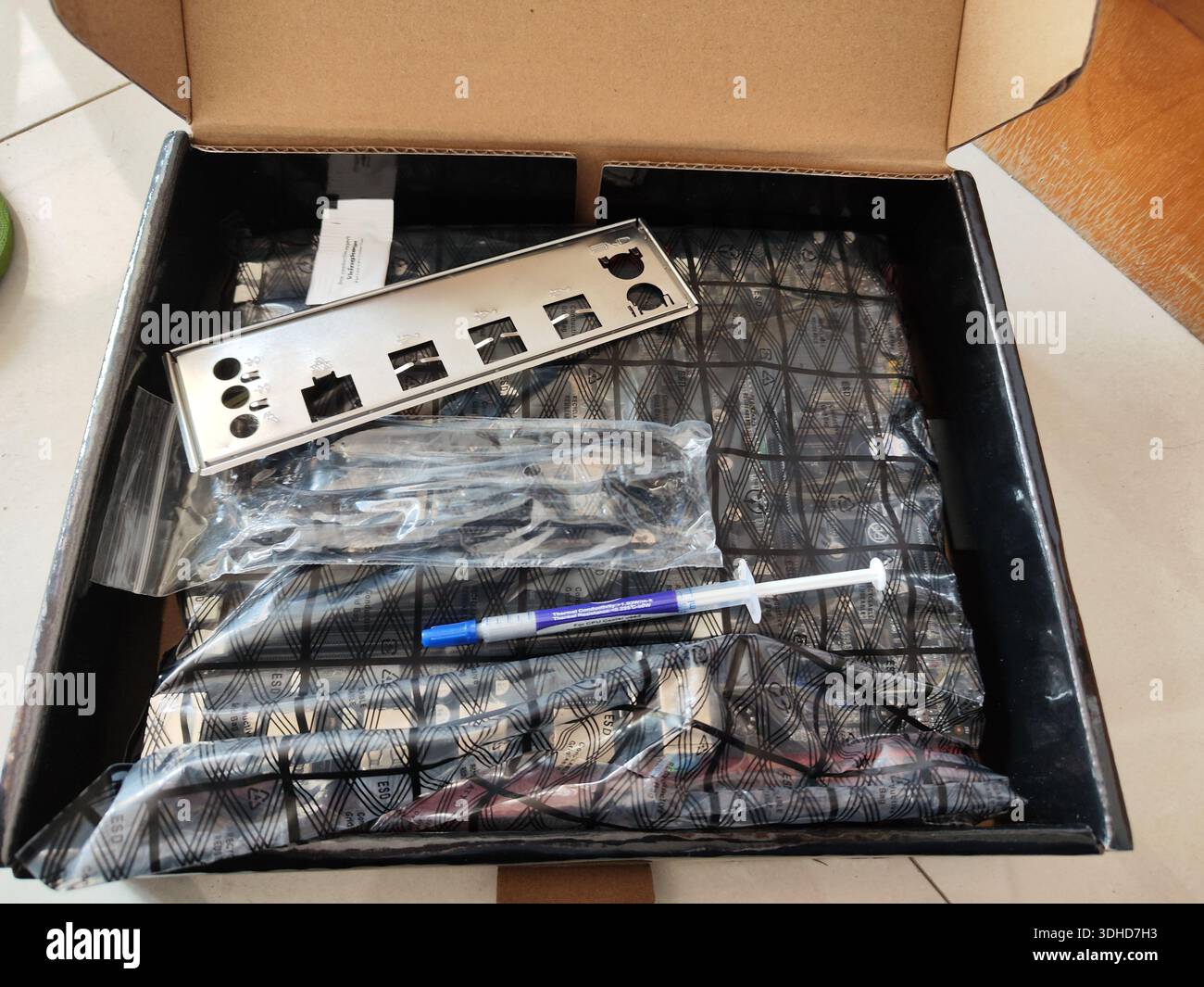 Open box containing computer motherboard components and thermal paste syringe Stock Photo