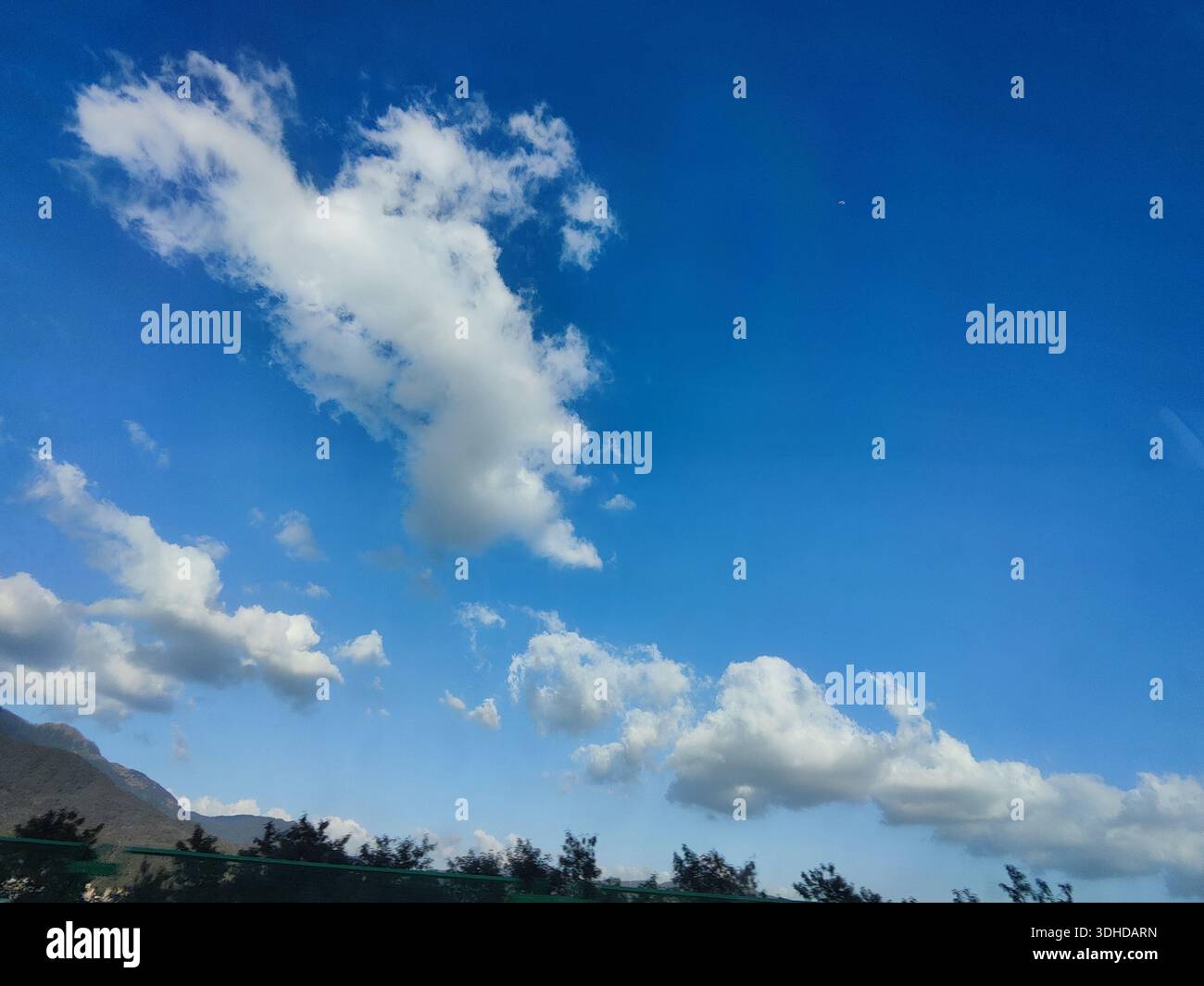 Dramatic Clouds Against a Vibrant Blue Sky with Mountain Silhouette Stock Photo